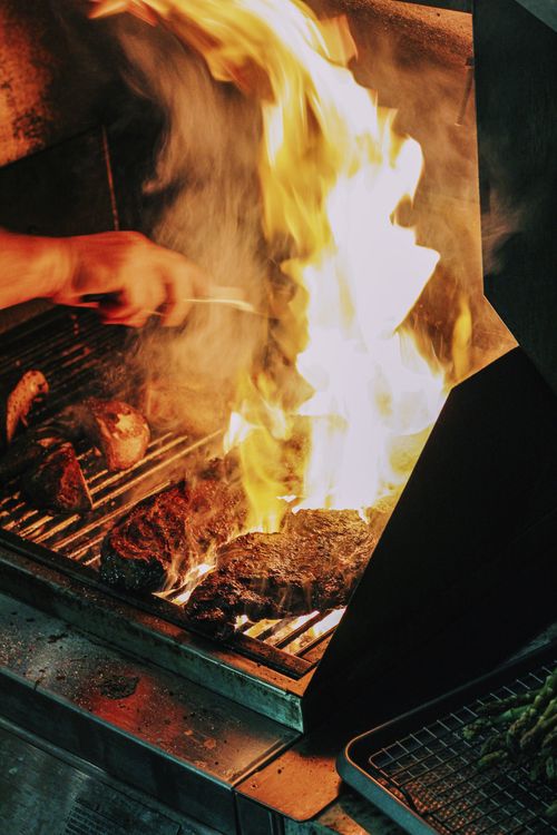 Steaks searing over a live barbecue flame