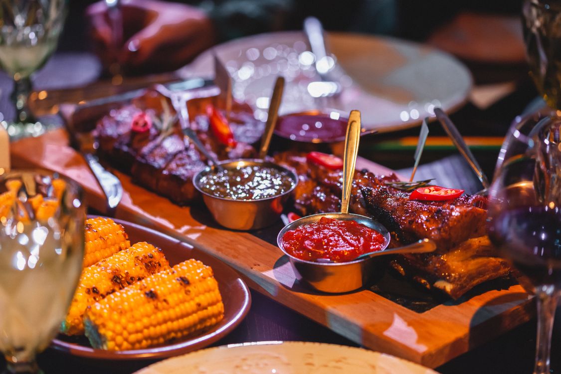 Glazed ribs on a board with corn and sauce